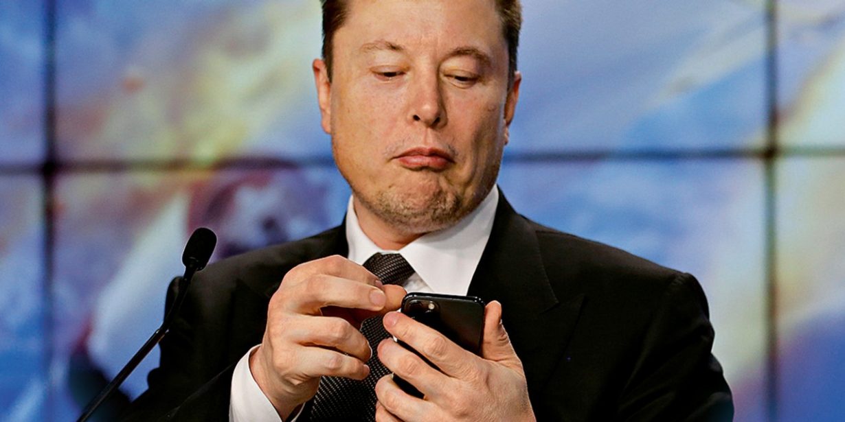 Elon Musk sieht auf sein Smartphone.