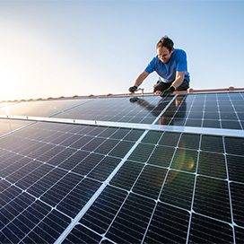 Ein Arbeiter verlegt Solarpanele auf einem Dach