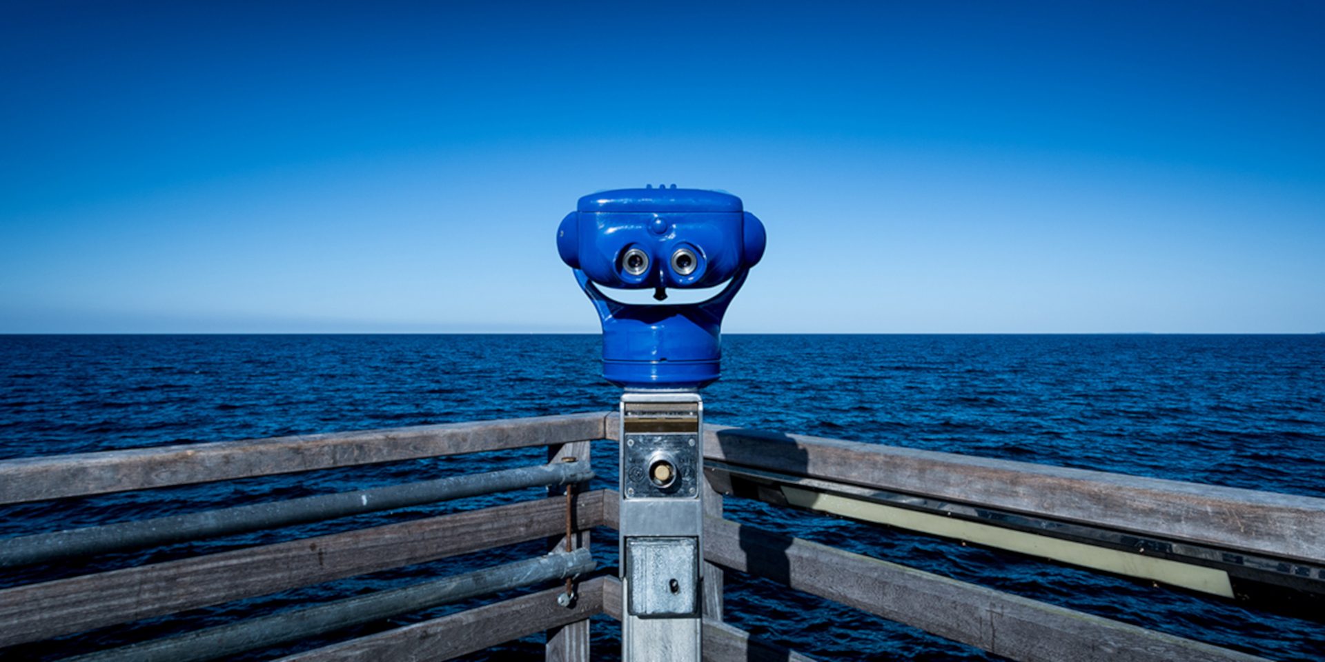 Stationäres Fernglas auf einer Seebrücke mit Blick auf das Meer.