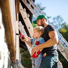 Mann und Kind streichen ein Haus