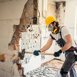 Arbeiter schlägt mit Hammer eine Wand ein.