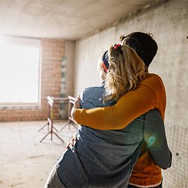 Getty Images/Skynsher umarmende Personen stehen in einem Rohbau