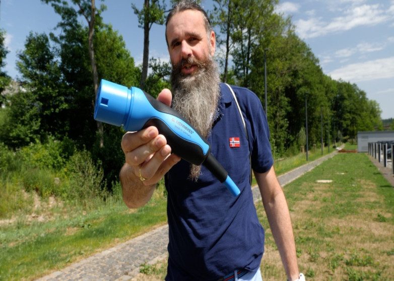 Mann streckt Stecker in die Kamera